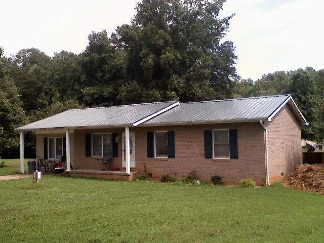Gray metal roof on a brick ranch house with a side carport in Sheridan