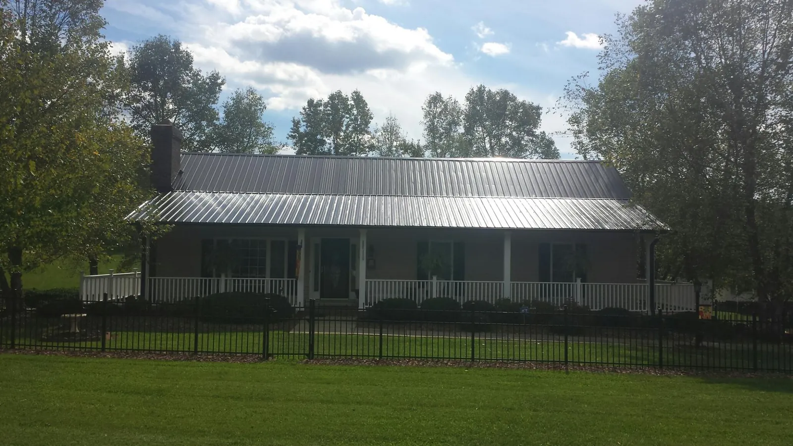 Gray metal roof on a brick ranch with a full width front porch — Gutter Guard Installation work by our crew in Sheridan